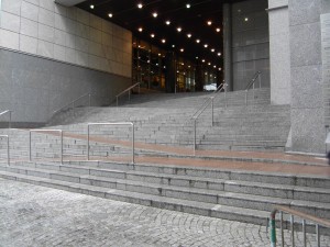 Colour photograph showing the same dangerous public ramp/stair combination near the Main Public Entrance to the European Parliament Building, on Rue Wiertz, in Brussels. During rush hour periods of the working day, this external ramp/stair combination is a very busy public pedestrian route. Click to enlarge. This photograph taken by CJ Walsh. 2010-02-24. For more photographs of this architectural gem, dating from 2000-2001, see SDI's Corporate WebSite.