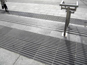 Colour photograph showing details of the steps, handrails and tactile ground surface indicators at the Main Entrance to the New Criminal Courts of Justice Building in Dublin, Ireland. Photograph taken by CJ Walsh. 2011-03-30. Click to enlarge.
