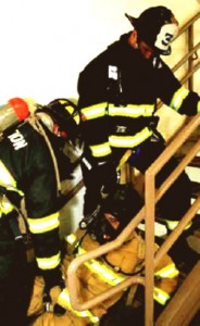 Colour photograph showing an injured, or impaired, firefighter being assisted by two colleagues in an upward staircase removal exercise. For reasons outlined in a previous post (2010-12-13) ... all three firefighters must continue to wear full Personal Protection Equipment (PPE) ... and use Self-Contained Breathing Apparatus (SCBA). Click to enlarge.