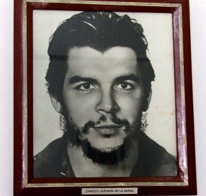 Colour photograph showing a framed head and shoulders of the young Dr. Ernesto 'CHE' Guevara de la Serna Lynch in a small museum in the central square of Yara (Plaza Grito de Yara), Cuba. Centuries earlier, nearby, the Indian hero Hatuey was burned at the stake. Photograph by CJ Walsh. 2007-04-10. Click to enlarge.